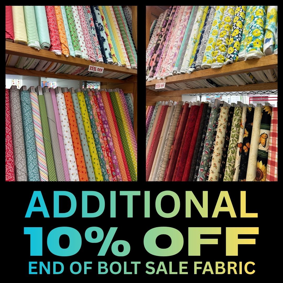 Colorful fabric bolts with sale offer signs.