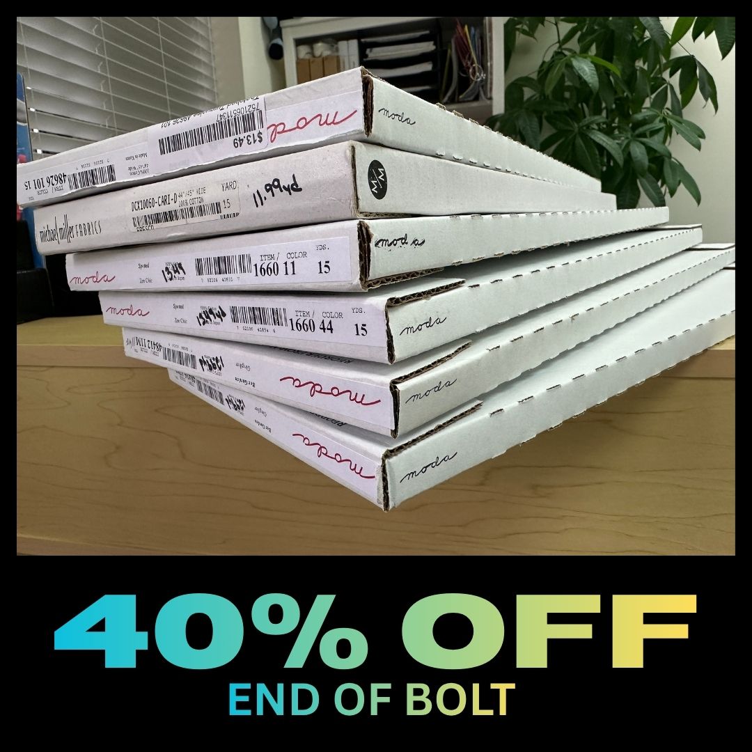 Stacked fabric bolts with 40% off sign.
