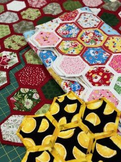 Colorful hexagon quilt pieces on a table.