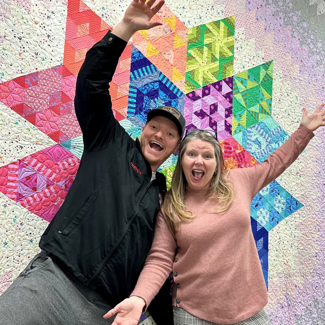 Carrie and Trevor Merchant in front of Tula Pink Nebula quilt