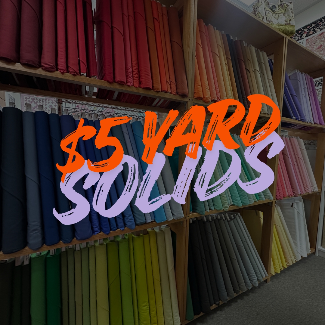 Colorful fabric bolts with $5 Yard Solids sign.